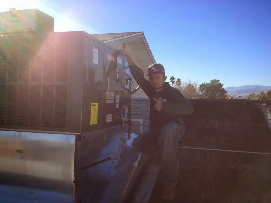 HVAC technician performing Air Duct Cleaning on a rooftop unit in Buda